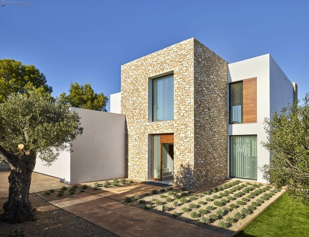 A modern, two-story home with a stone facade, wood accents, and a landscaped front yard.