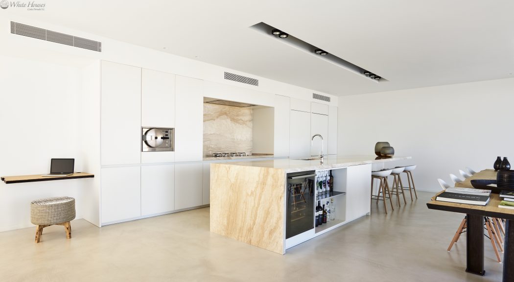 Sleek, minimalist kitchen with wood-paneled island, built-in appliances, and recessed lighting.