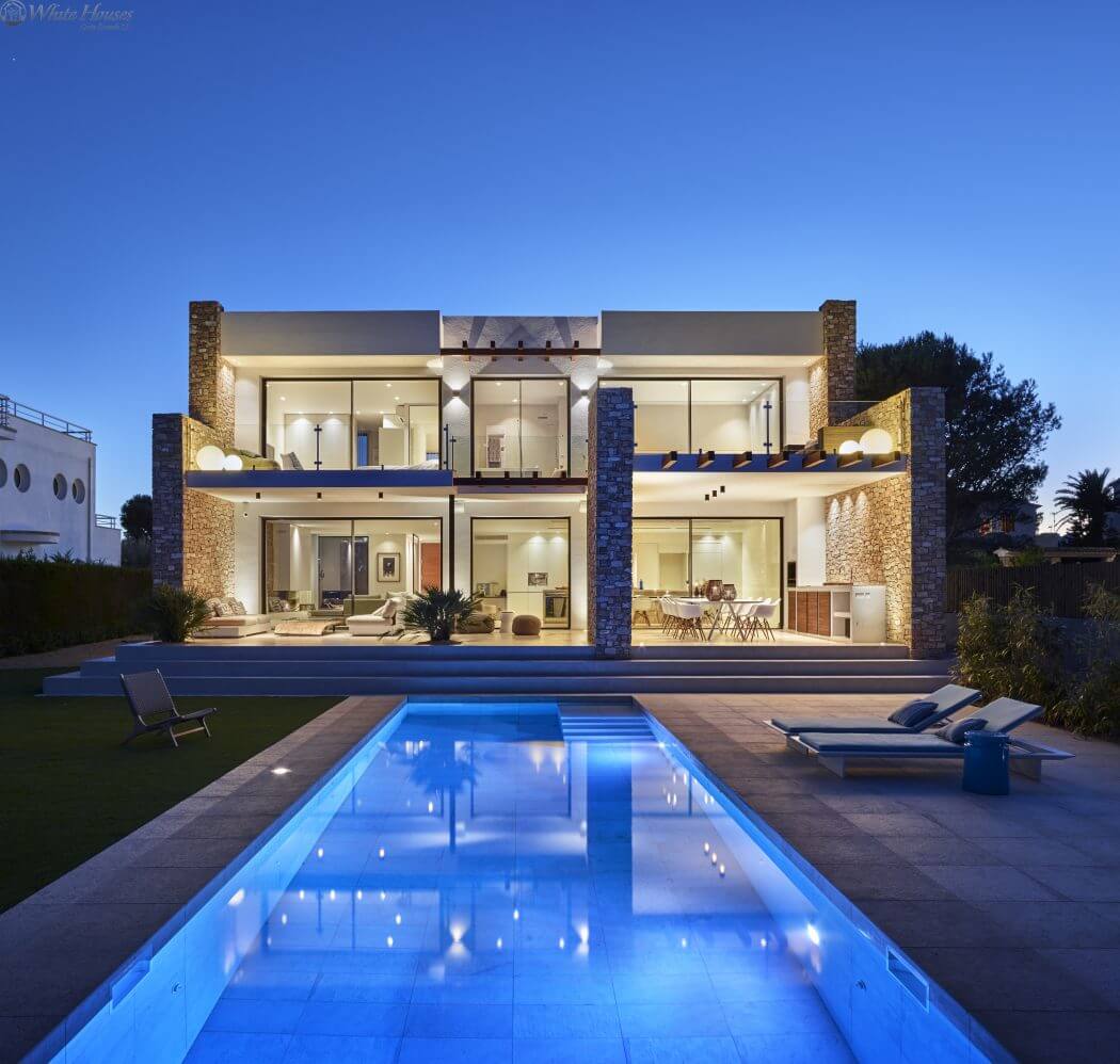 A modern luxury home with an expansive poolside patio, stone accents, and sleek design.