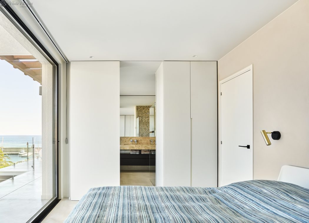Spacious bedroom with floor-to-ceiling windows, neutral color palette, and built-in storage.