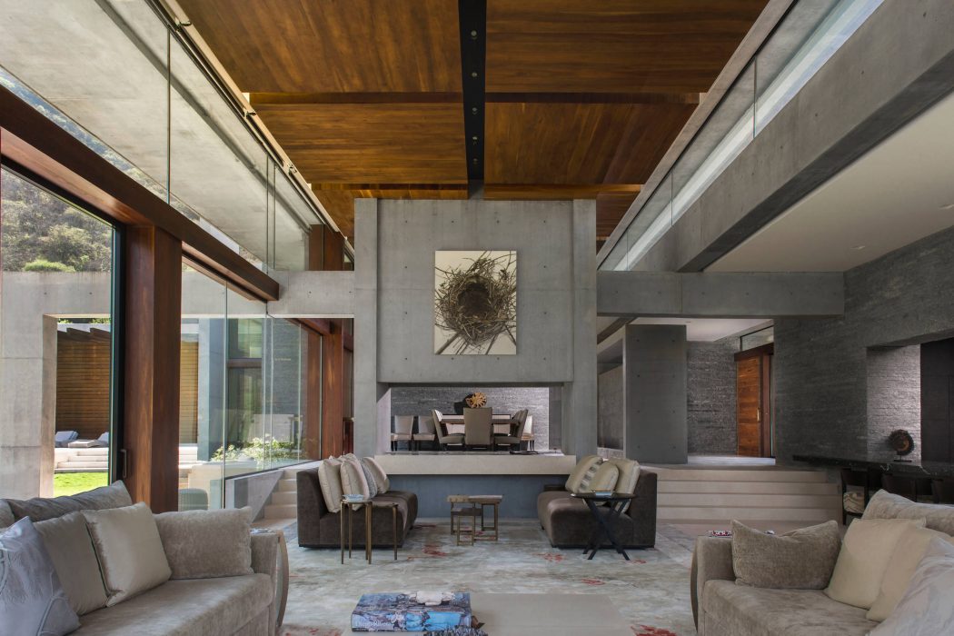 Striking modern interior features exposed concrete walls, wood ceilings, and a large fireplace.