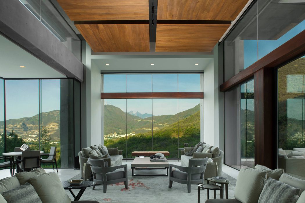 Stunning contemporary living room with wooden ceiling, large windows offering mountain views.
