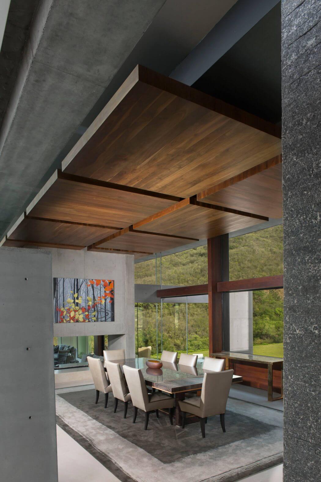 Striking modern dining room with exposed concrete walls, wood-paneled ceiling, and panoramic view.
