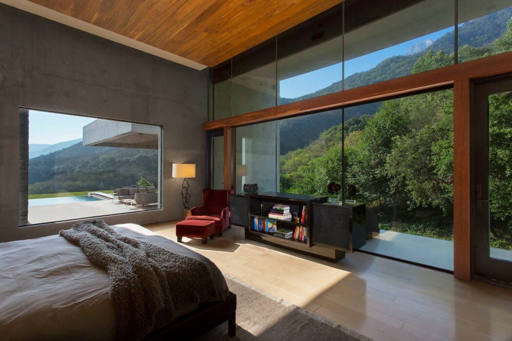 Spacious, modern bedroom with large glass walls showcasing scenic mountain views.