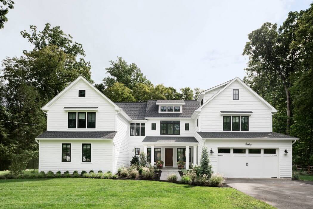 Expansive two-story farmhouse-style home with white siding, large windows, and a prominent porch.