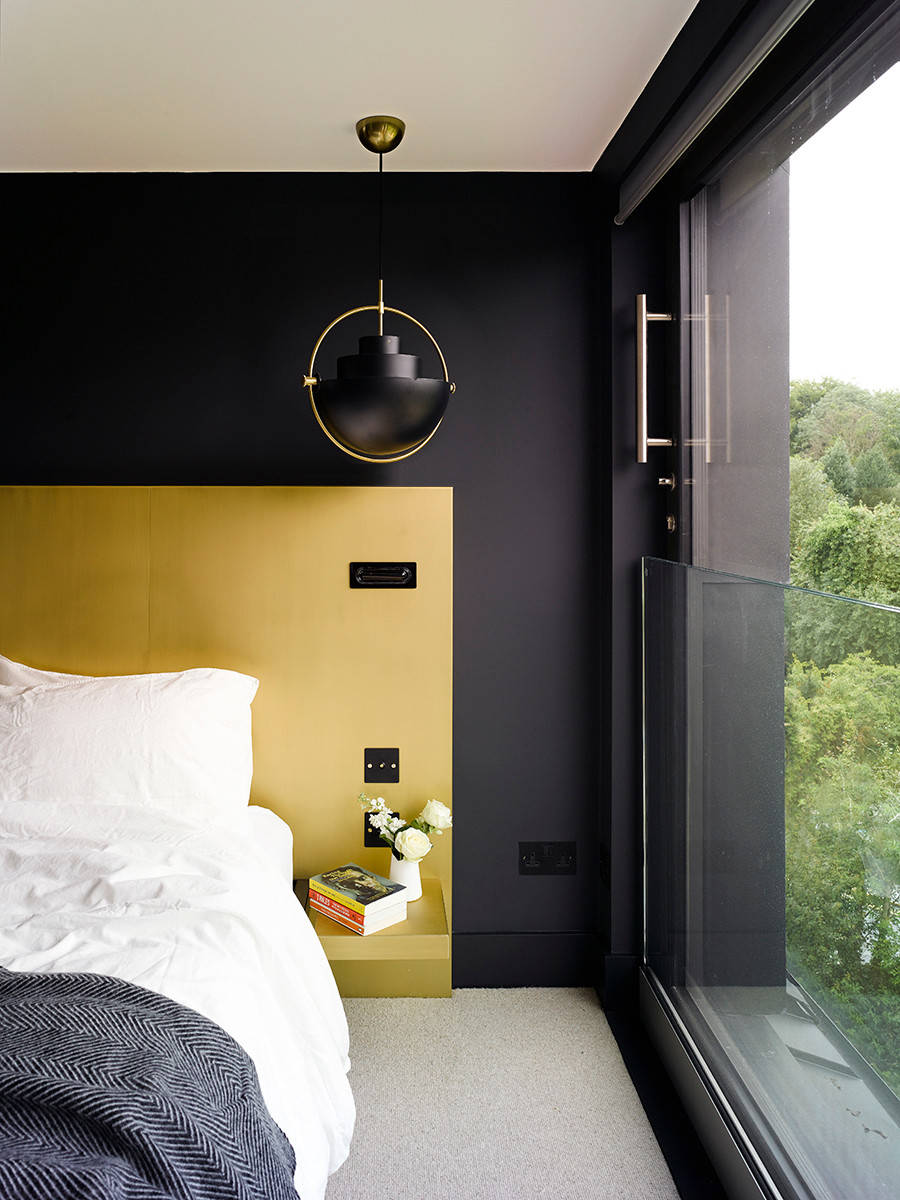 Sleek and modern bedroom design with black walls, yellow accents, and a striking pendant light.