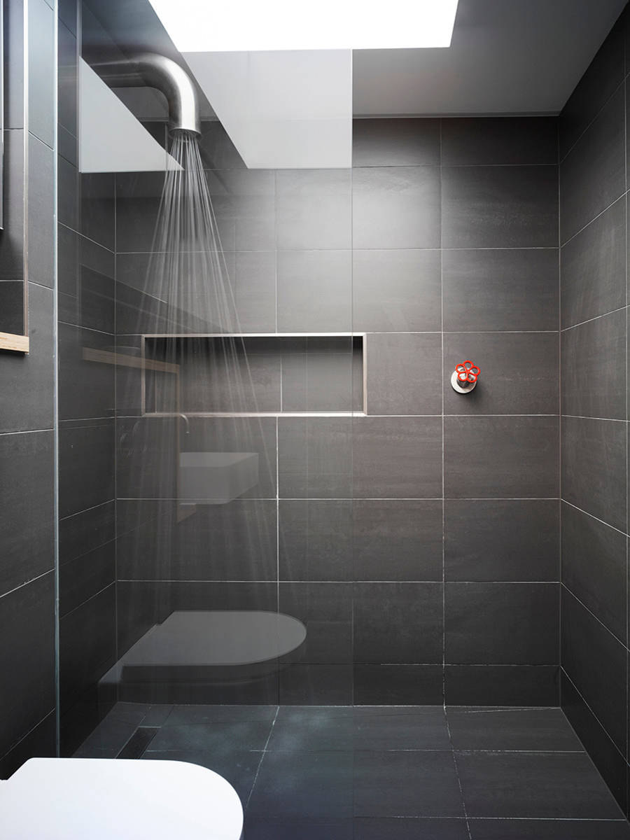 Sleek, minimalist bathroom with a tiled shower stall and built-in storage niche.