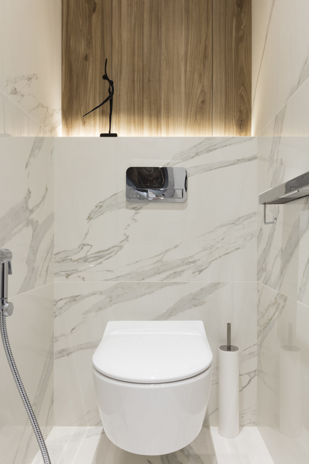 Modern bathroom with marble walls, wooden accents, and a closed toilet.