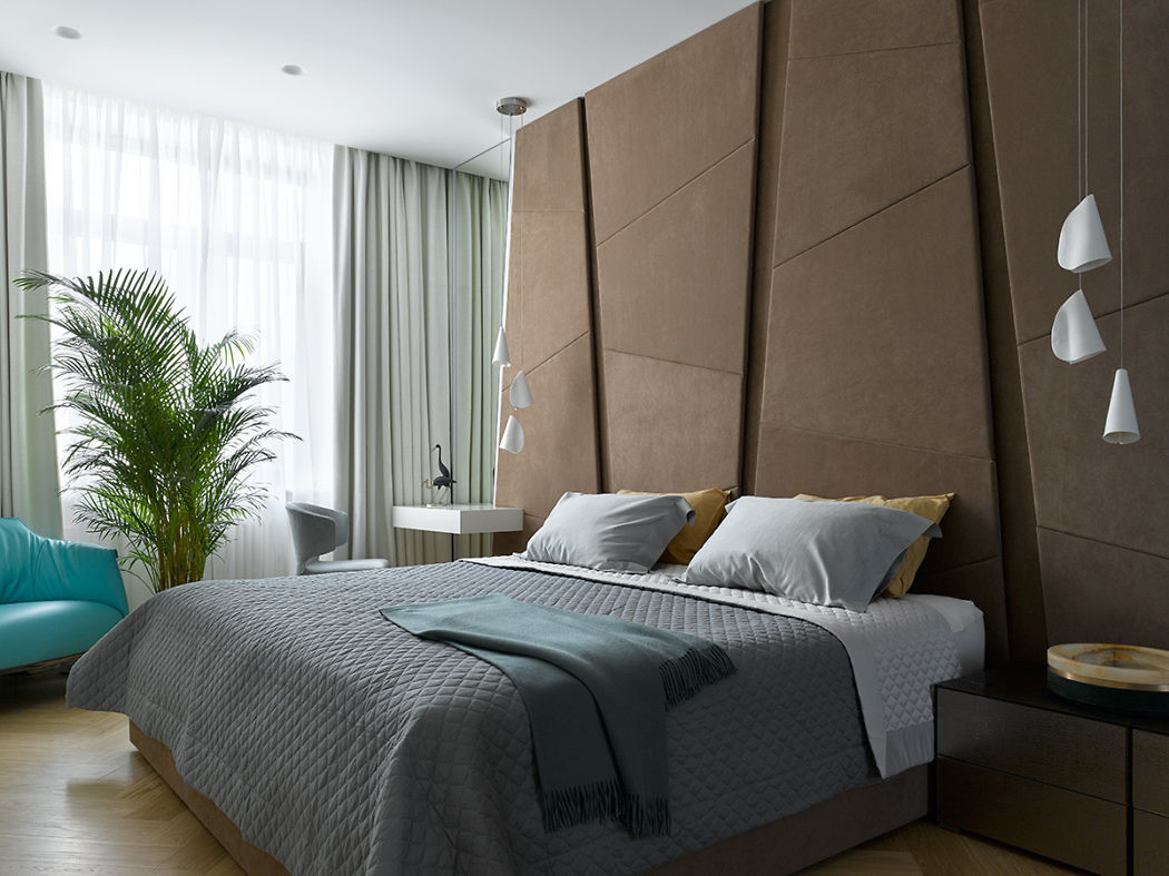 Contemporary bedroom with upholstered headboard and geometric lamps.