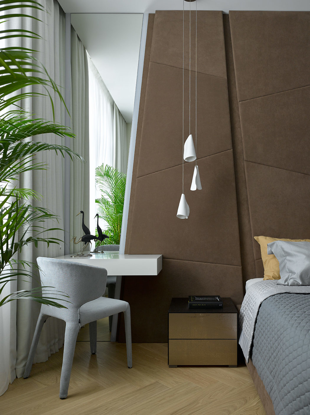 Modern bedroom with a study nook, upholstered wall panel, and pendant lights