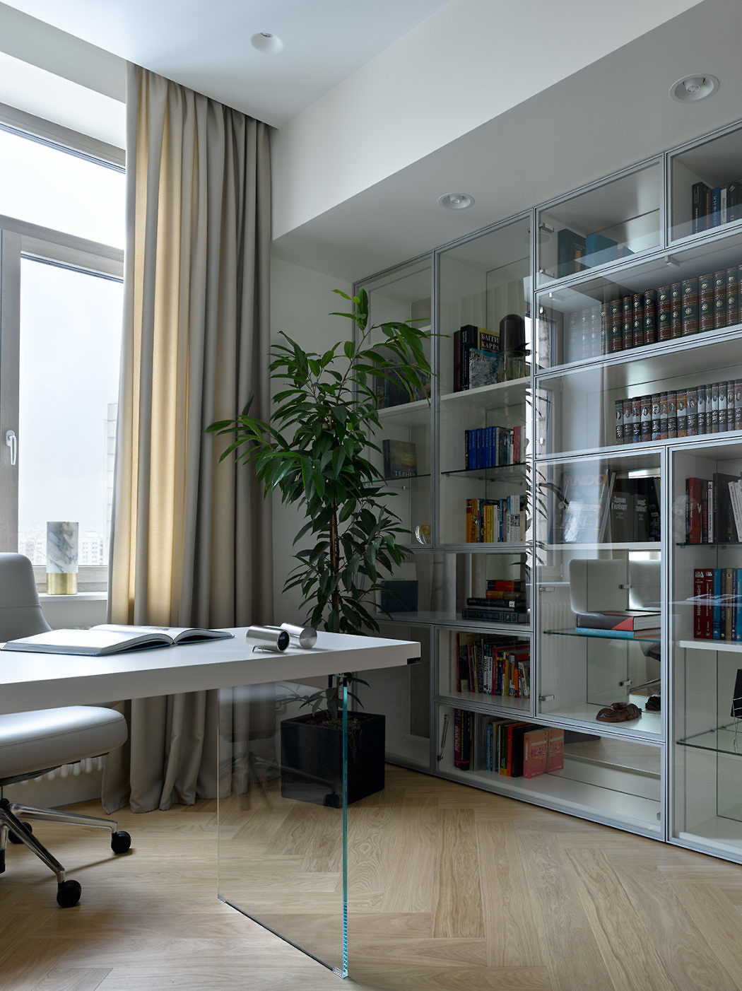 Modern home office with desk, chair, bookshelf, and large window.