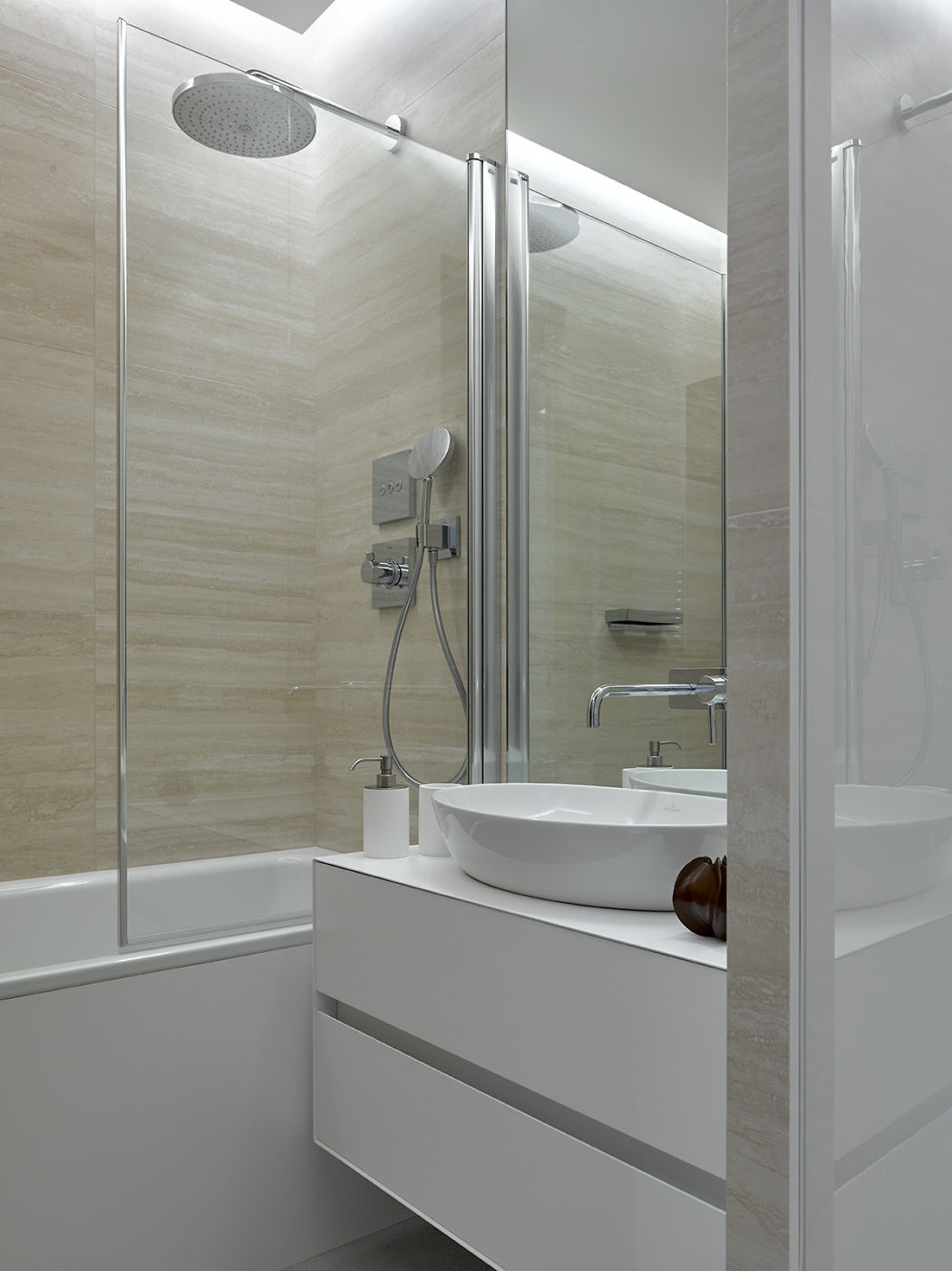 Modern bathroom with beige tiles, glass shower, and white vanity.