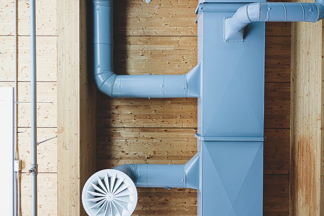 Contemporary exposed blue piping against wooden walls.