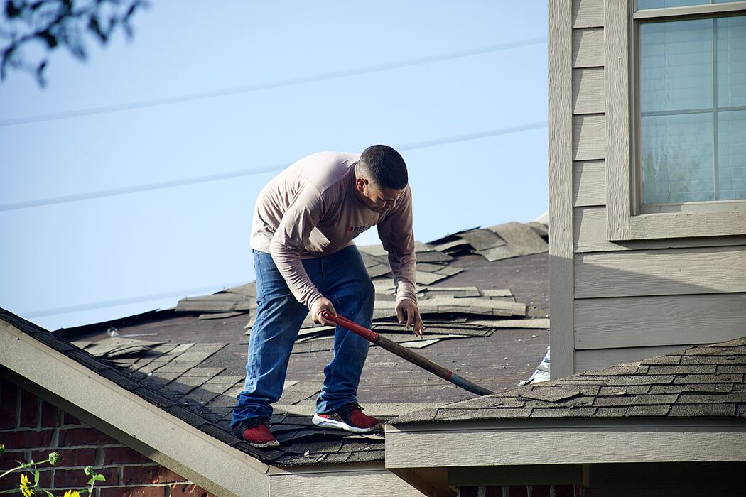 A person repairing a damaged house roof.