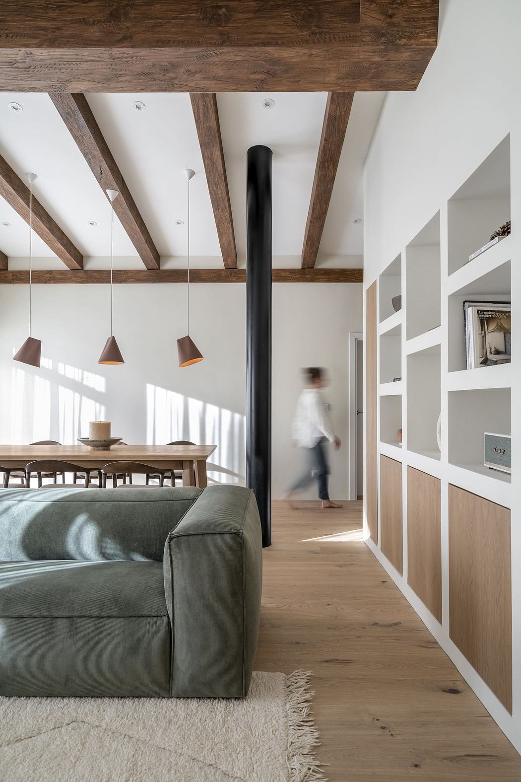 Modern living room with exposed beams and a white built-in bookshelf.