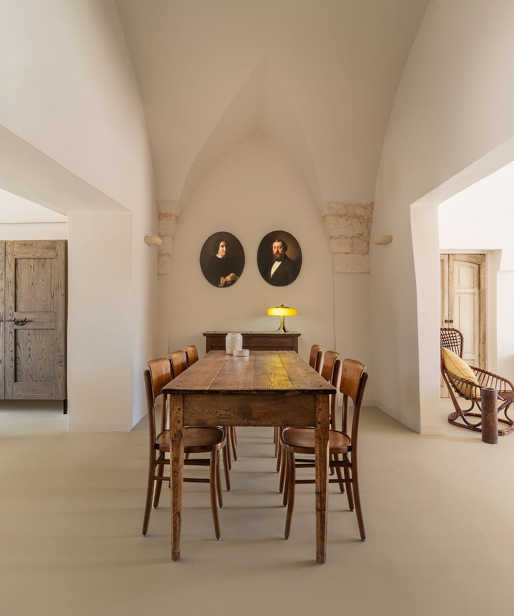 Elegant dining room with arched ceilings, classic wooden table, and portraits on