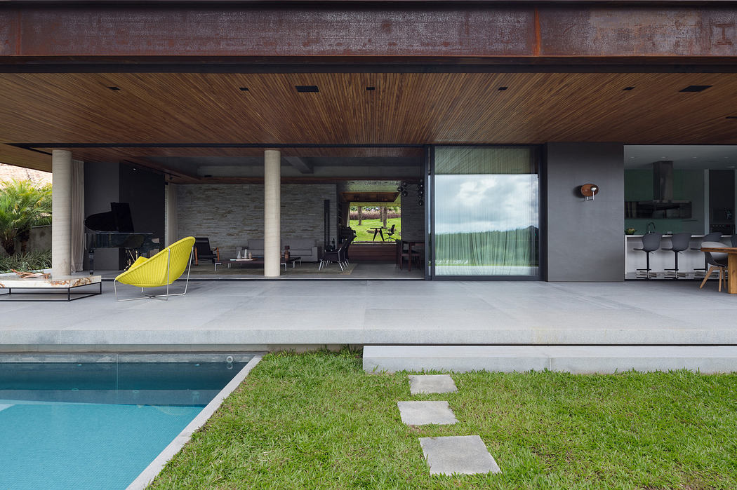 Modern home exterior with large glass windows, patio, and pool.