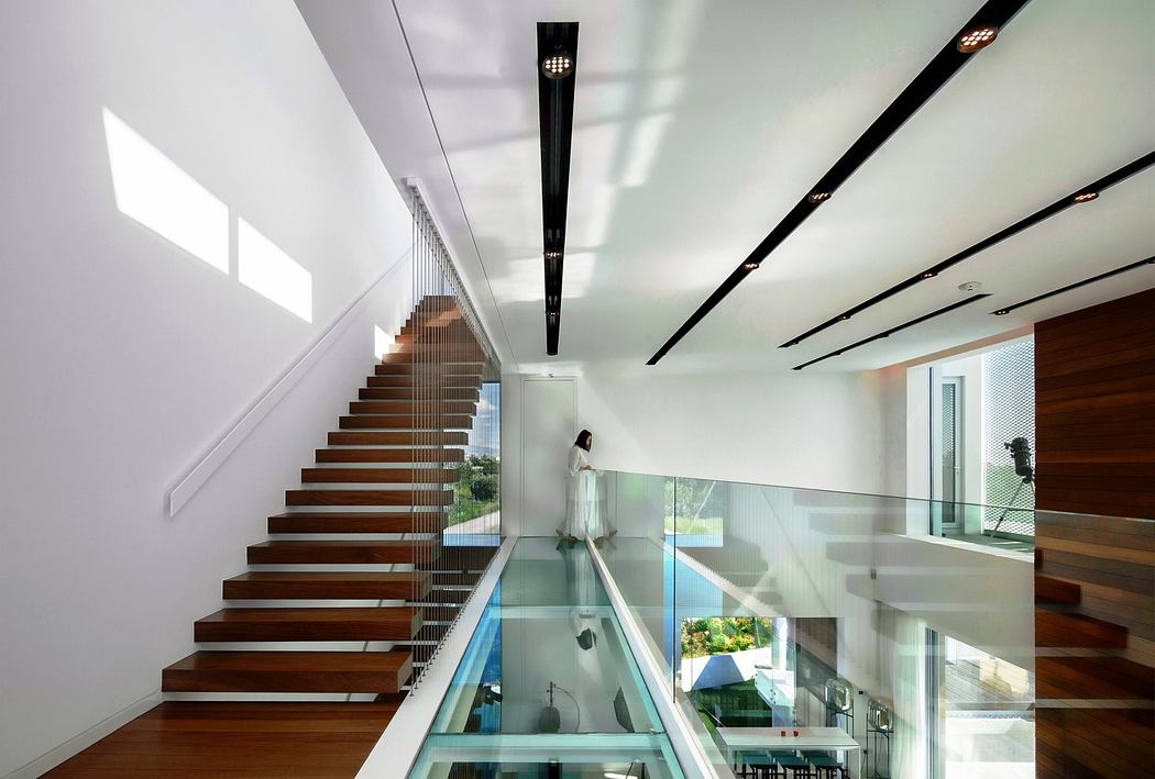 Modern interior with wooden staircase and glass floor overlooking a room below.