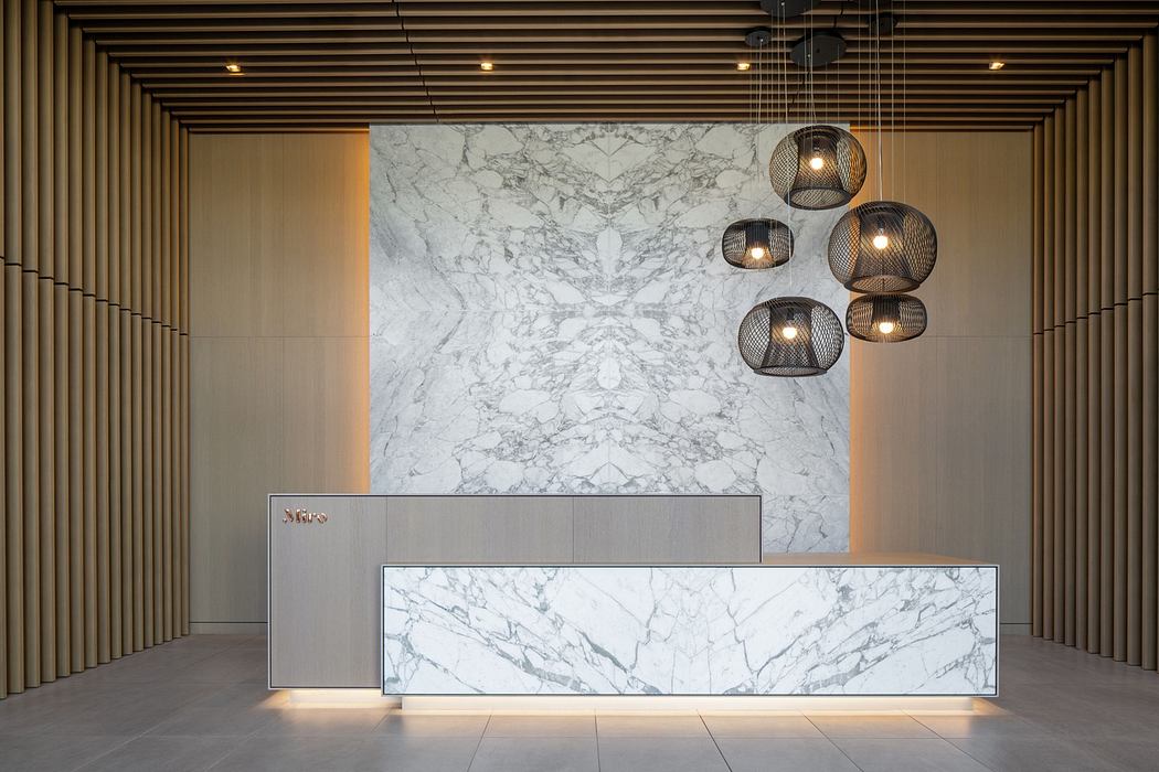 Modern lobby with marble reception desk and hanging basket lights.