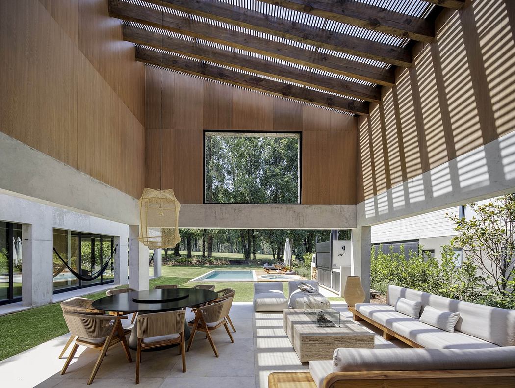 Modern living room with large windows, wooden ceiling, and minimalist furniture overlooking a pool