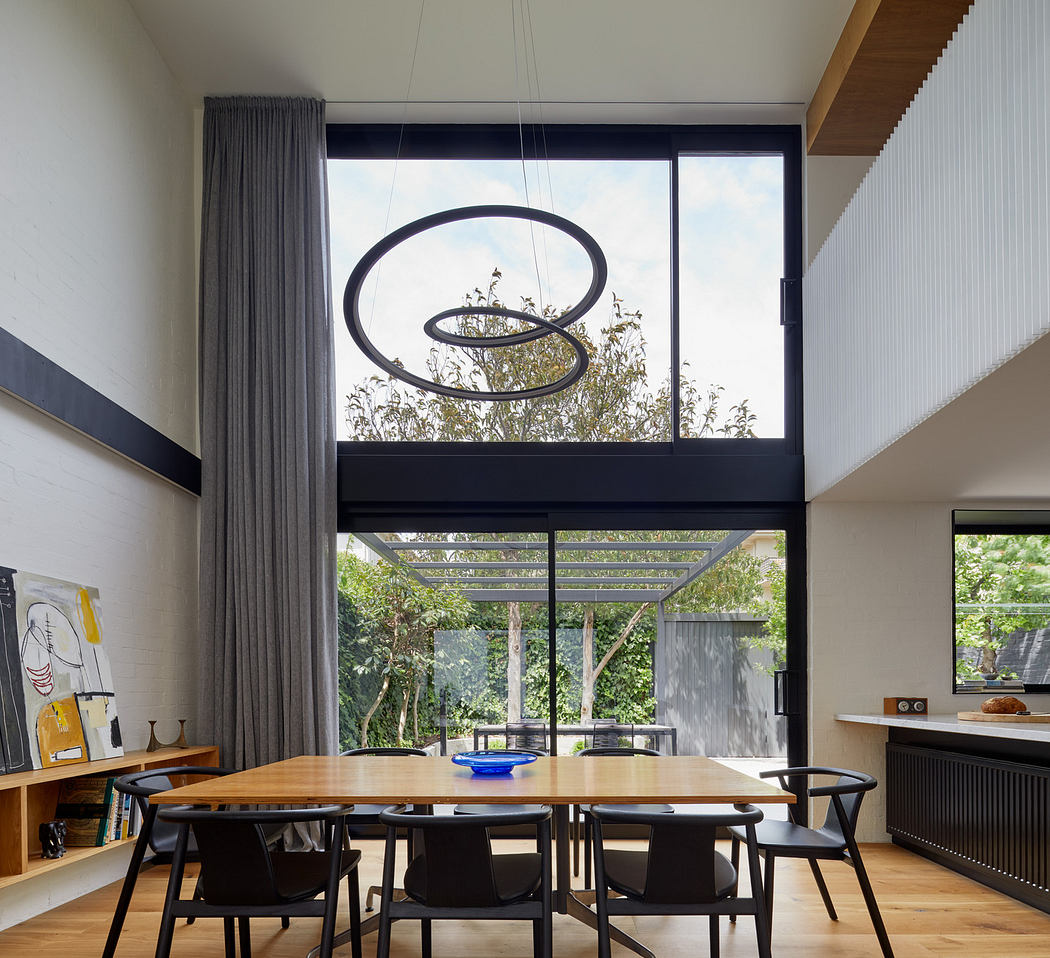 Modern dining room with large window, unique pendant light, and wooden table.
