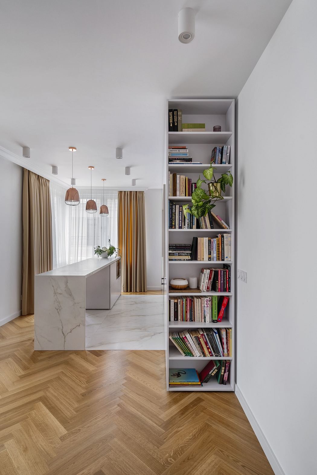 Modern kitchen with marble island, herringbone floor, and built-in bookshelf