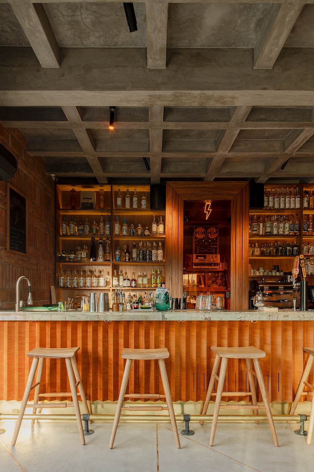 Modern bar interior with wooden accents and exposed concrete ceiling.