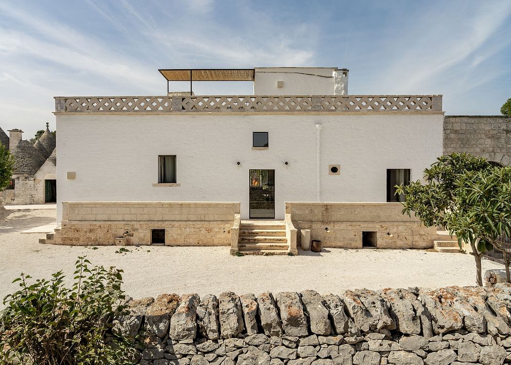 White traditional house with stone wall and courtyard.