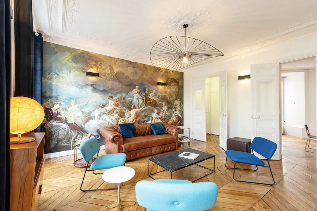 Elegant living room with classic mural, modern furniture, and hardwood floors.