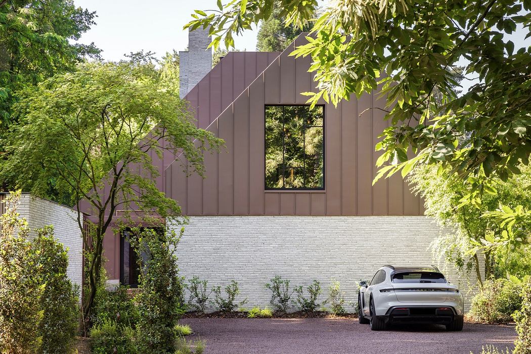 Modern house with brown panels, large windows, white brick base, surrounded by green