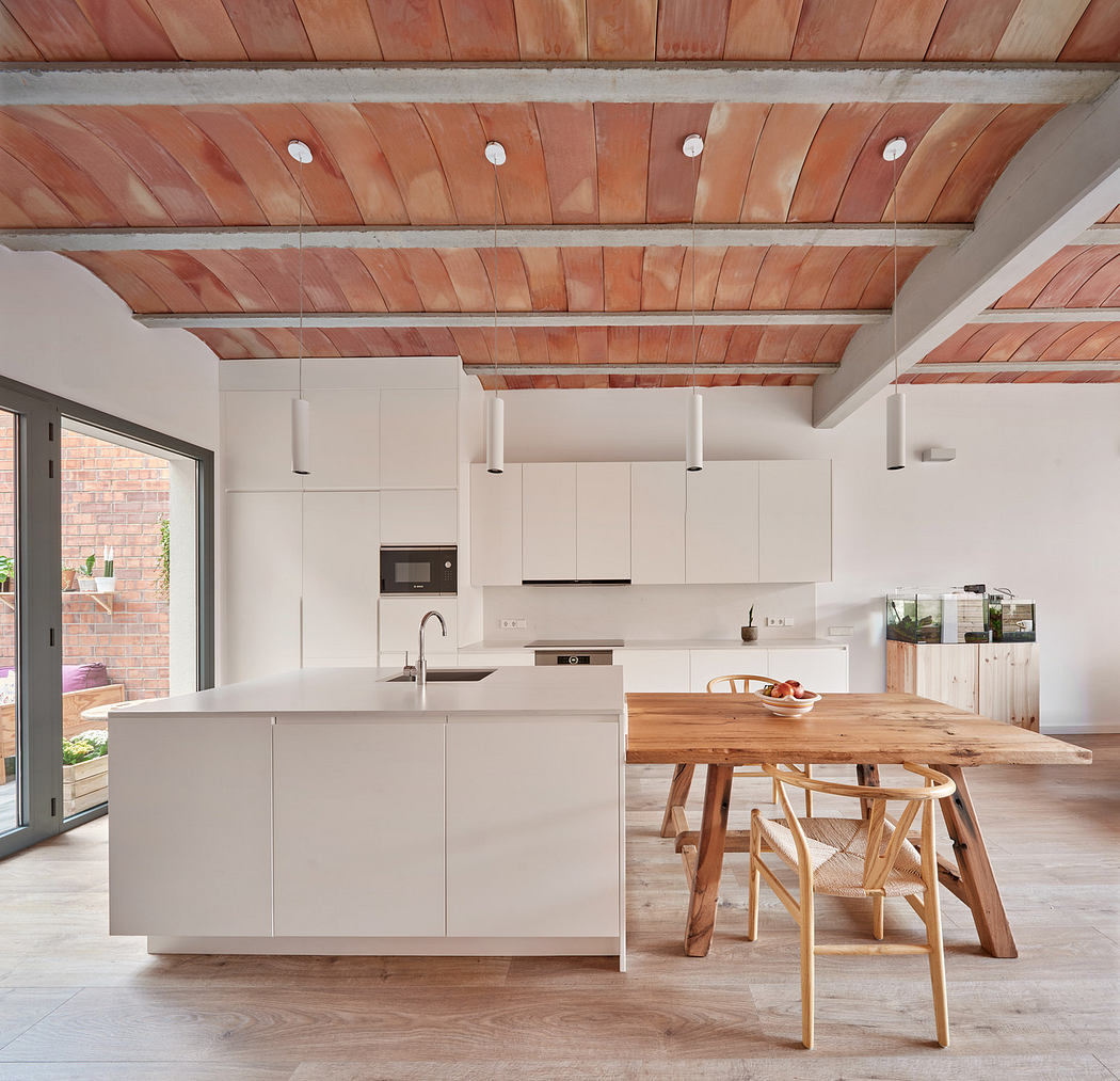 Modern kitchen with white cabinets, wooden ceiling, and dining table.