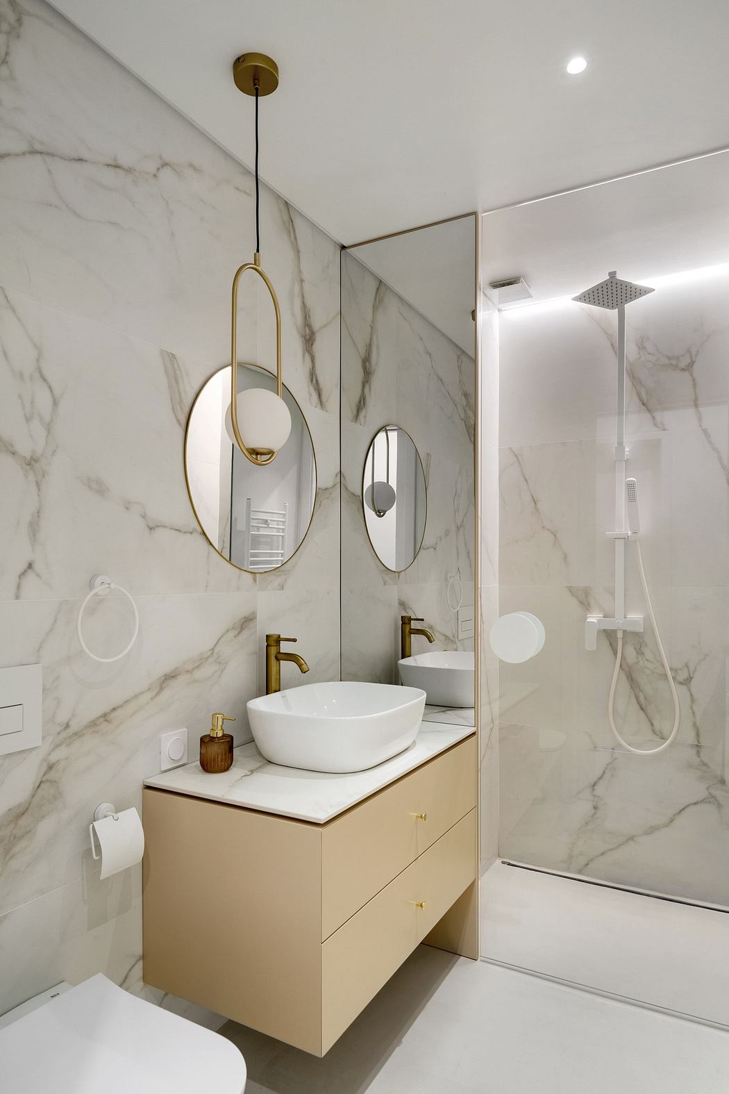 Modern bathroom with marble walls, a round mirror, and a vessel sink.
