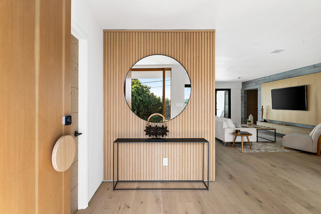 Modern living room with wooden slat partition, circular mirror, and minimalist furnishings.