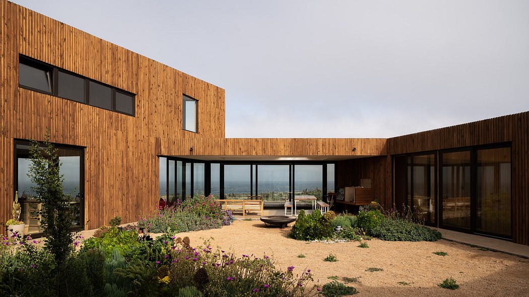 Modern wooden house with large windows overlooking the sea.