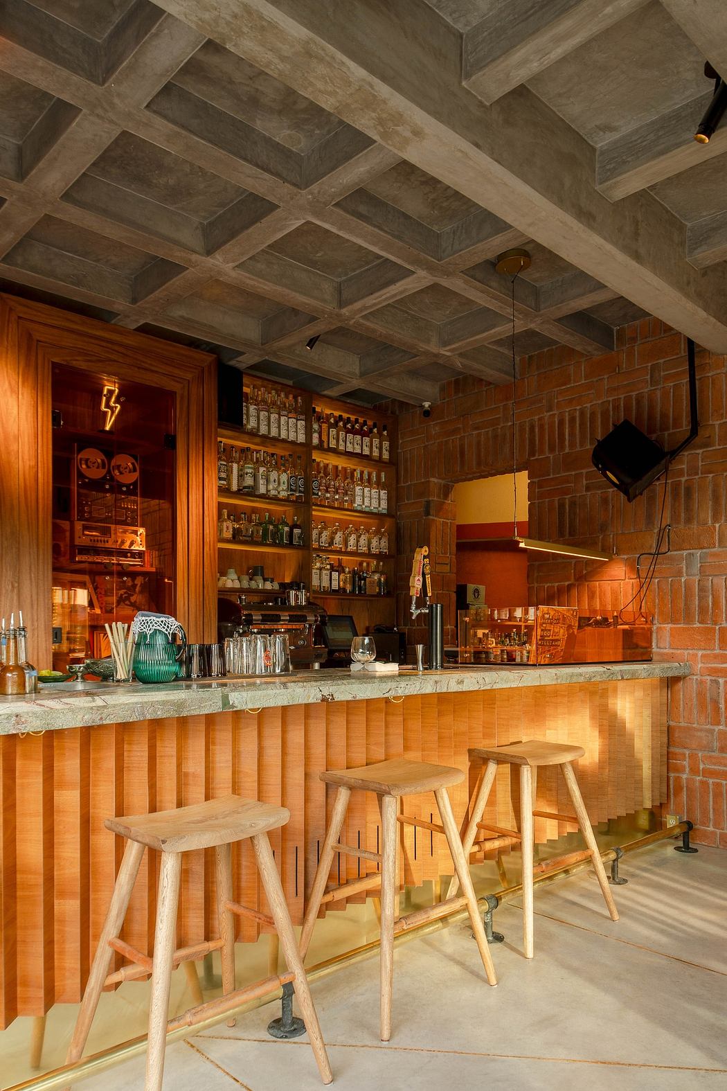 Modern bar interior with exposed concrete ceiling and brick walls, featuring wooden stools and countert