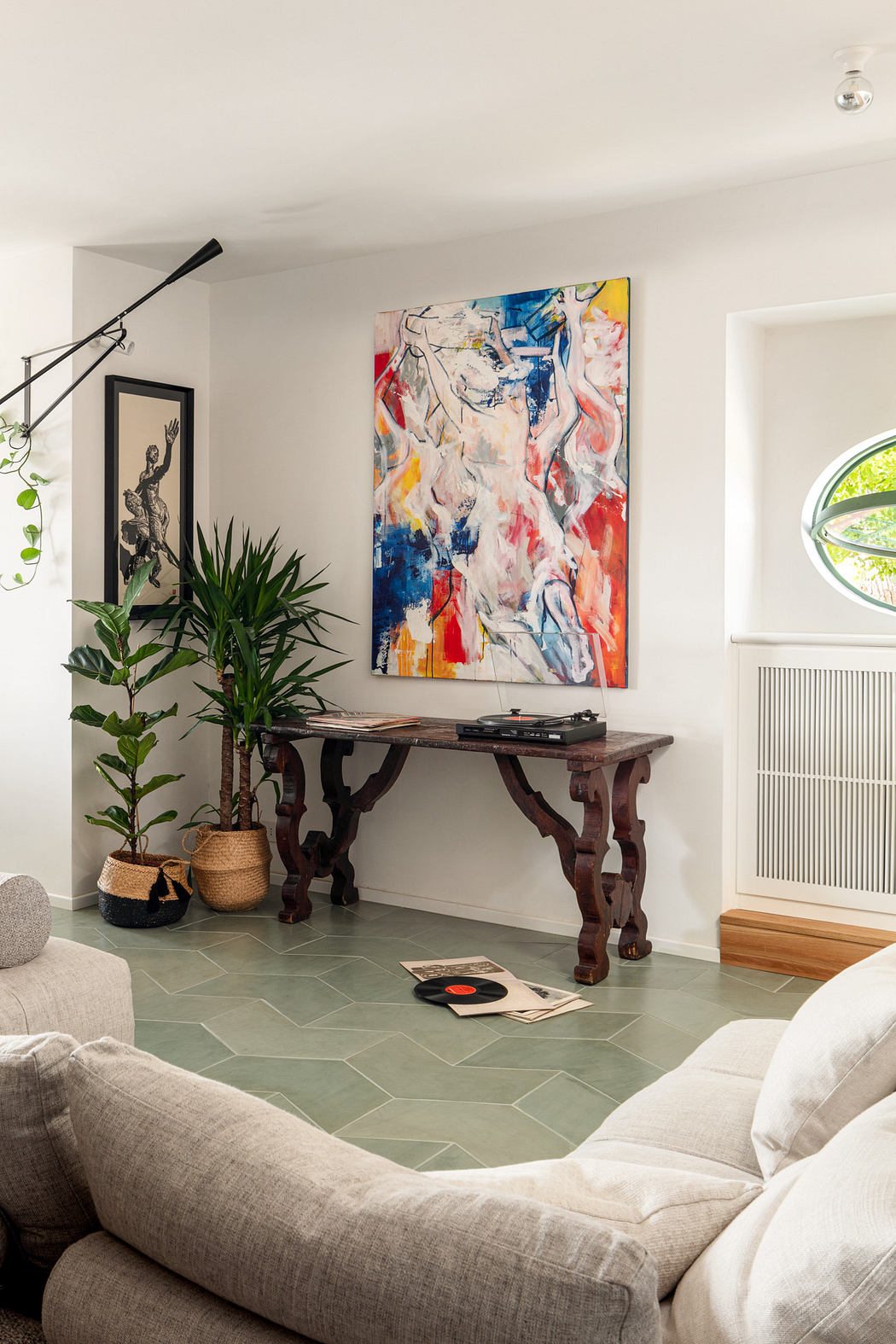 Modern living room with abstract art, antique table, and green plants.