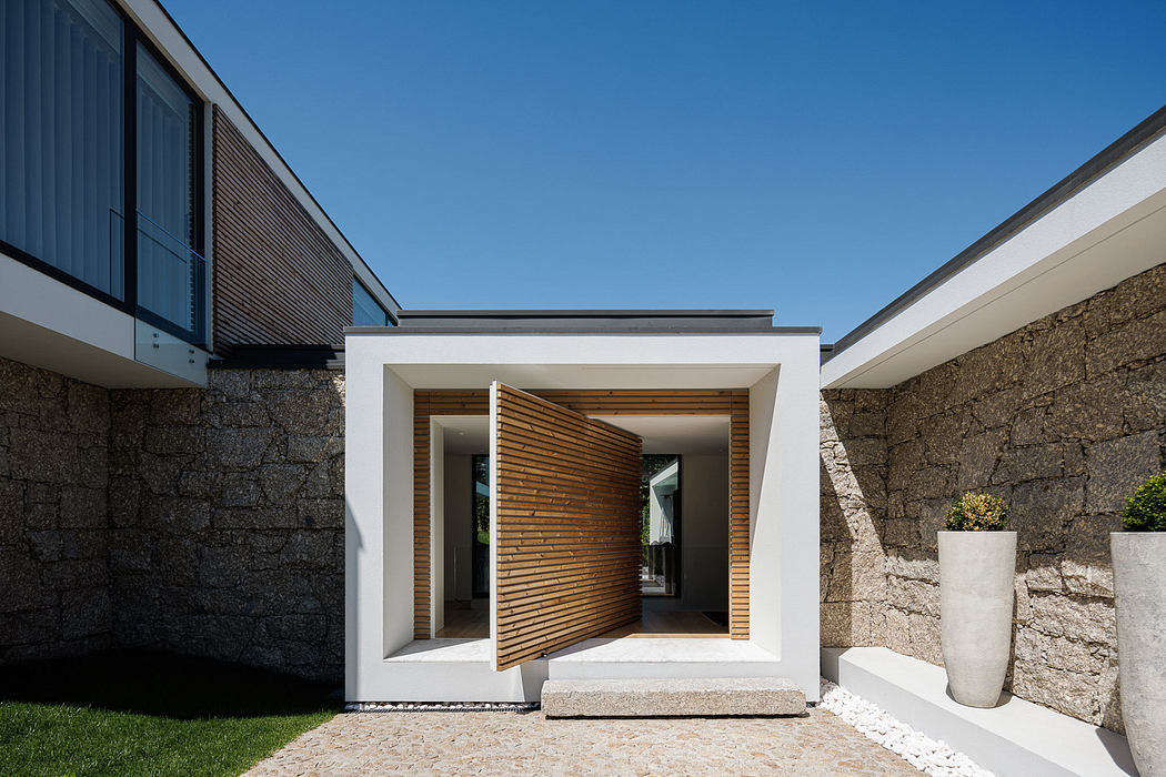 Modern home entrance with a slatted wooden door and stone walls.