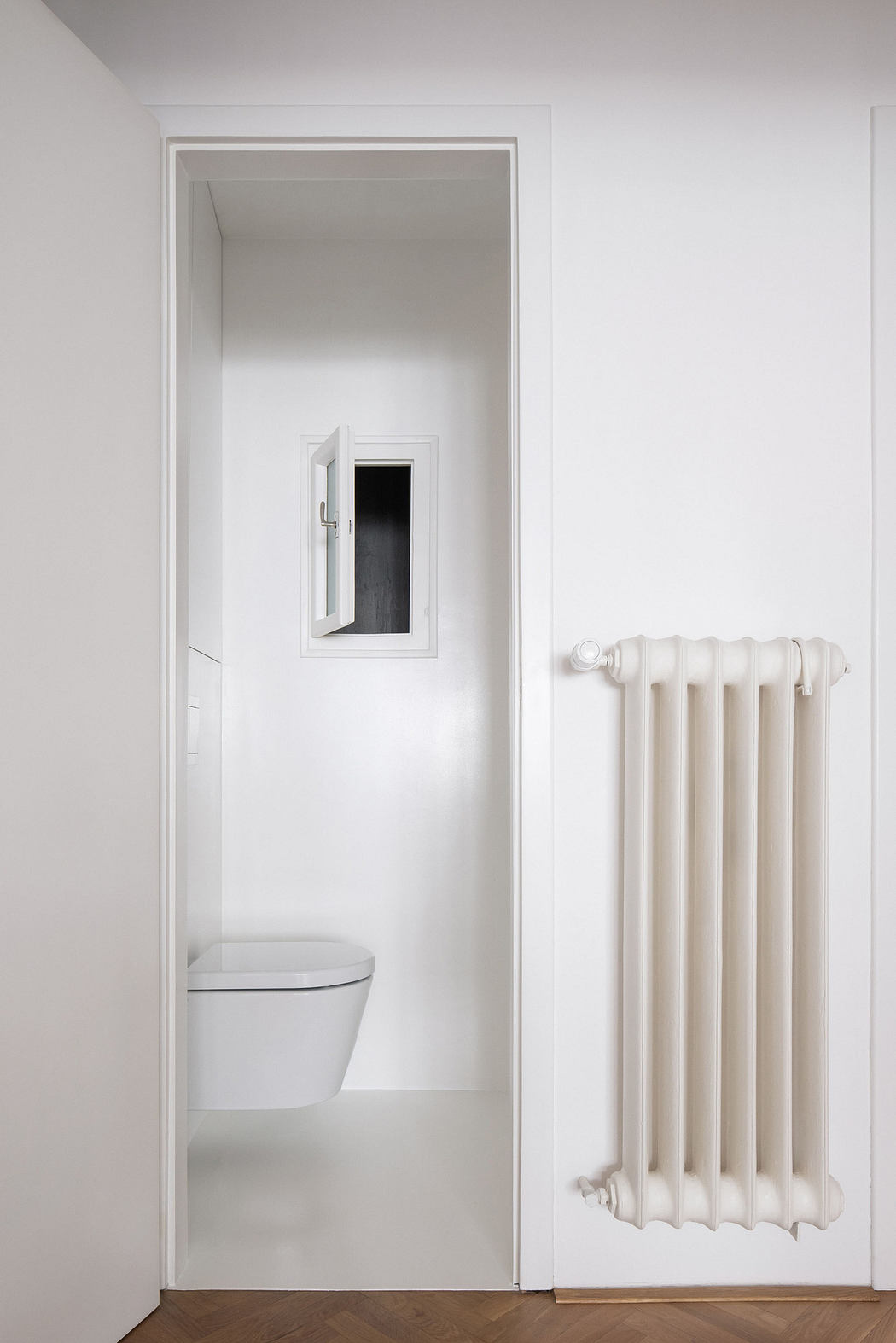 Modern bathroom entrance with a small window and a white radiator.