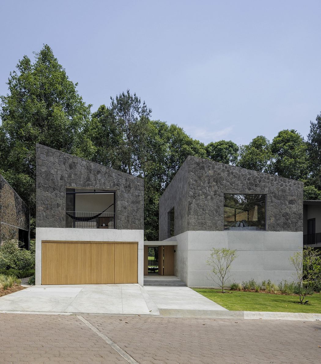 Modern two-story house with textured gray facade and wood garage door.