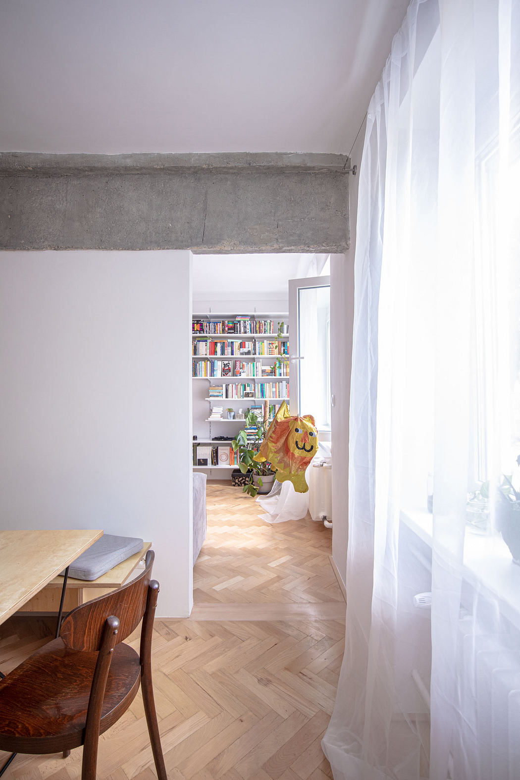 Bright, airy room with sheer curtains, wooden floors, and a built-in book