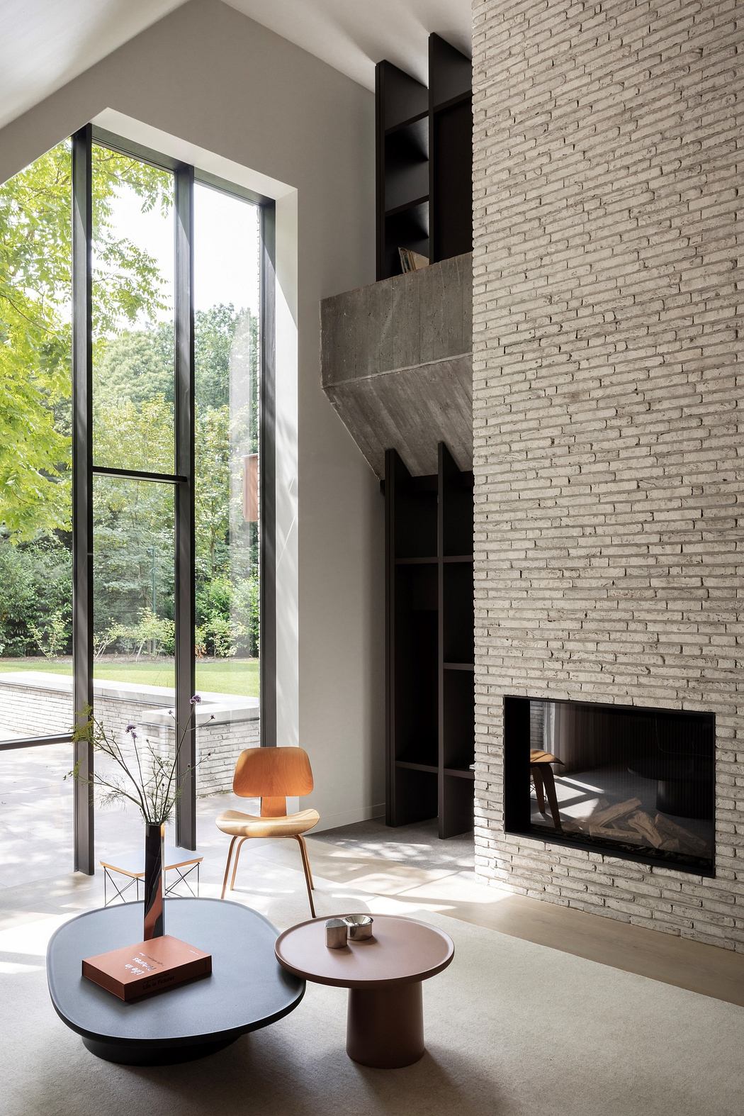 Modern living room with tall windows, brick wall, and minimalist furniture.