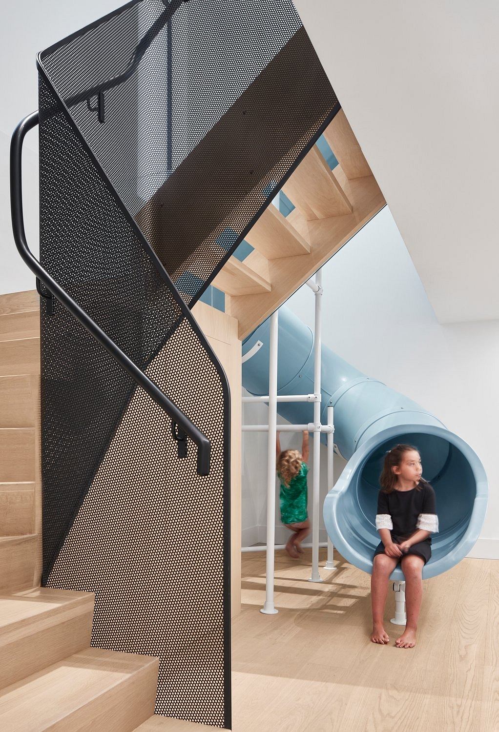 Modern staircase with integrated slide and children playing.