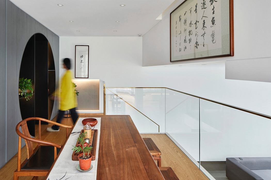 Modern interior with wooden table, glass railing, and Asian wall art.