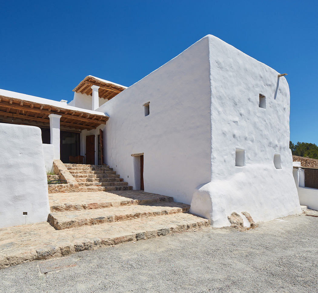 White traditional Mediterranean-style house with stone steps under a clear blue sky.