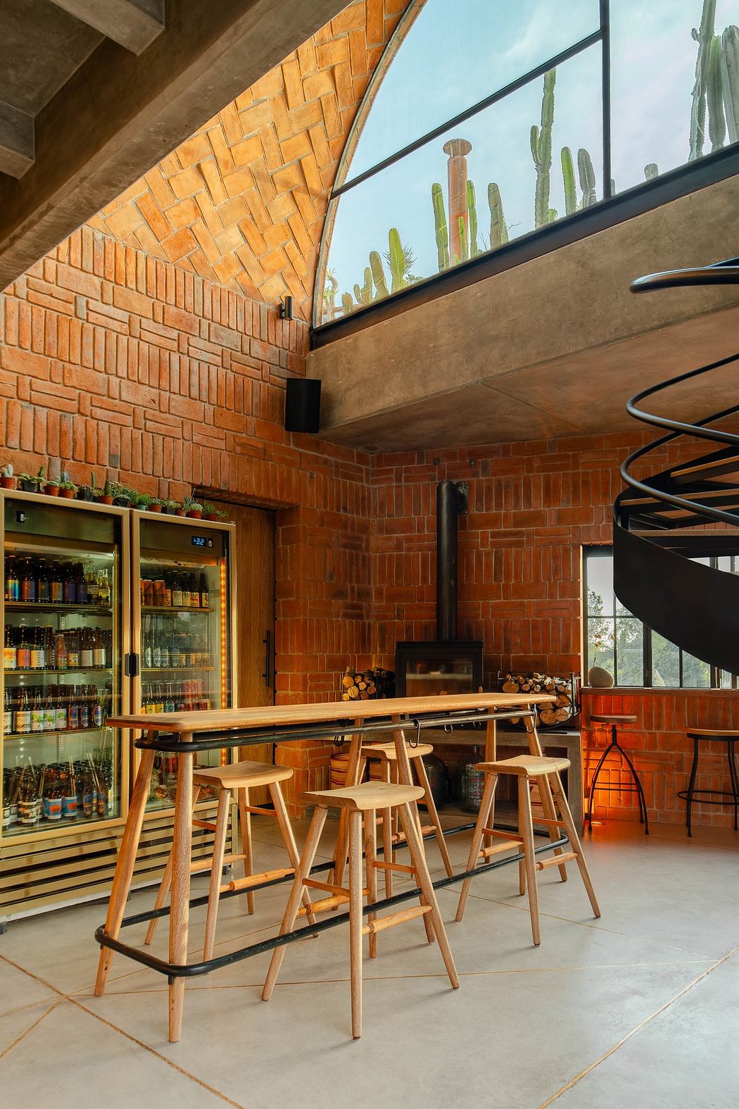 Modern café interior with brick walls, spiral staircase, and wooden stools.