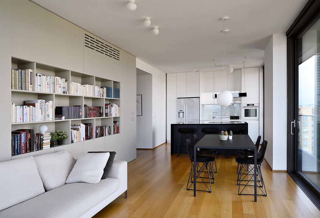 Modern apartment interior with minimalist furniture, bookshelf, and wooden floor.