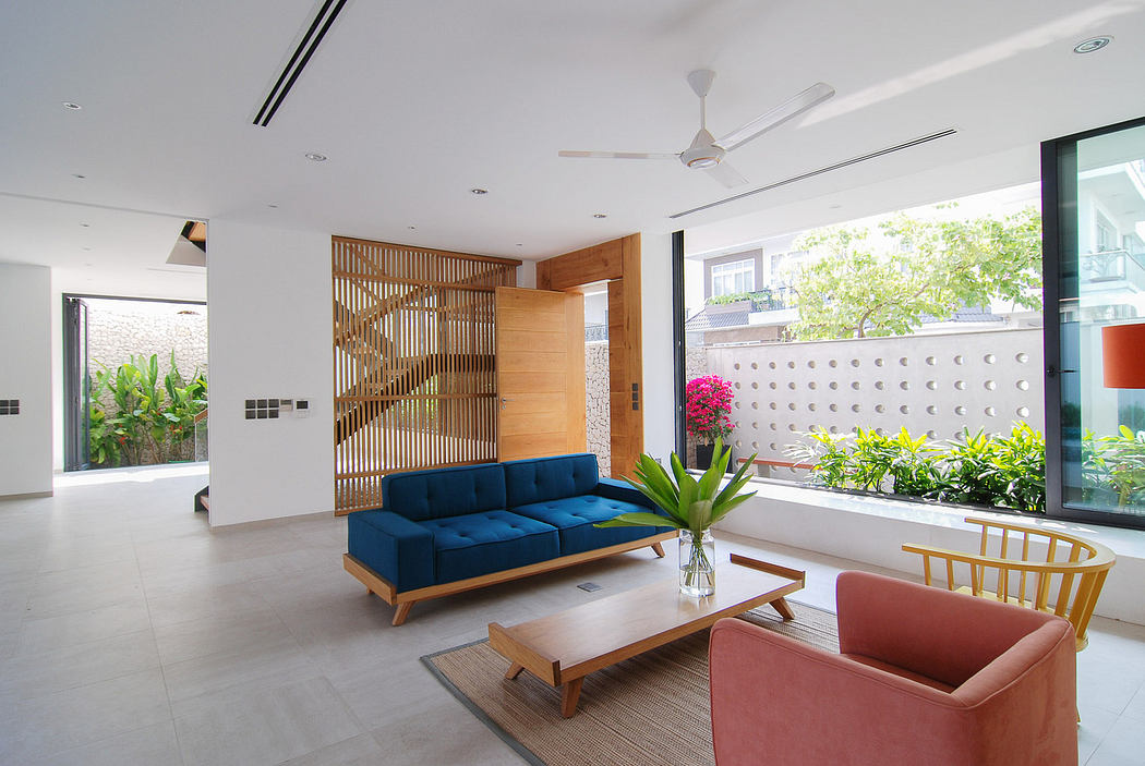 Modern living room with blue sofa, wooden divider, and garden view.