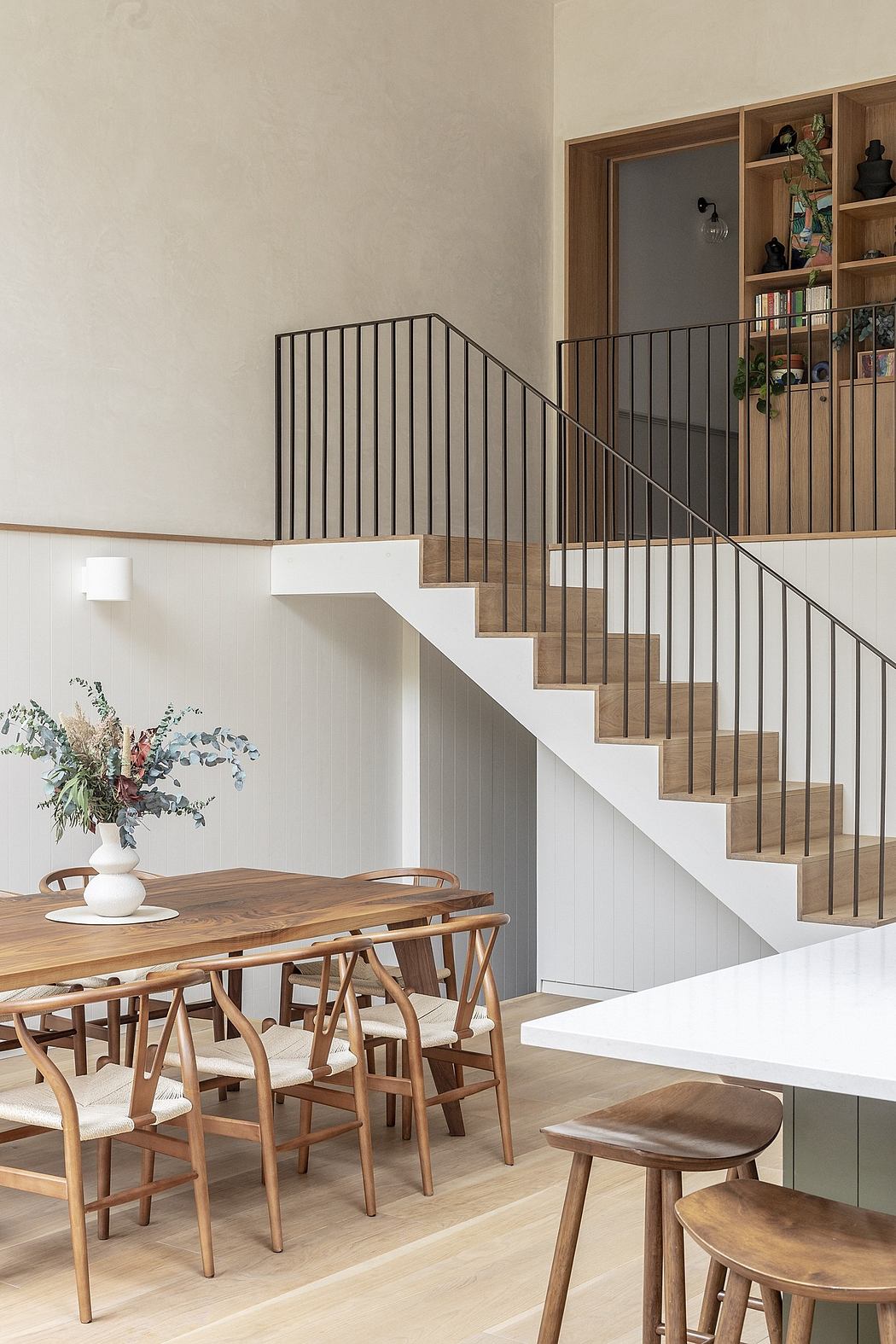 Modern dining room with wooden staircase and minimalist furniture.