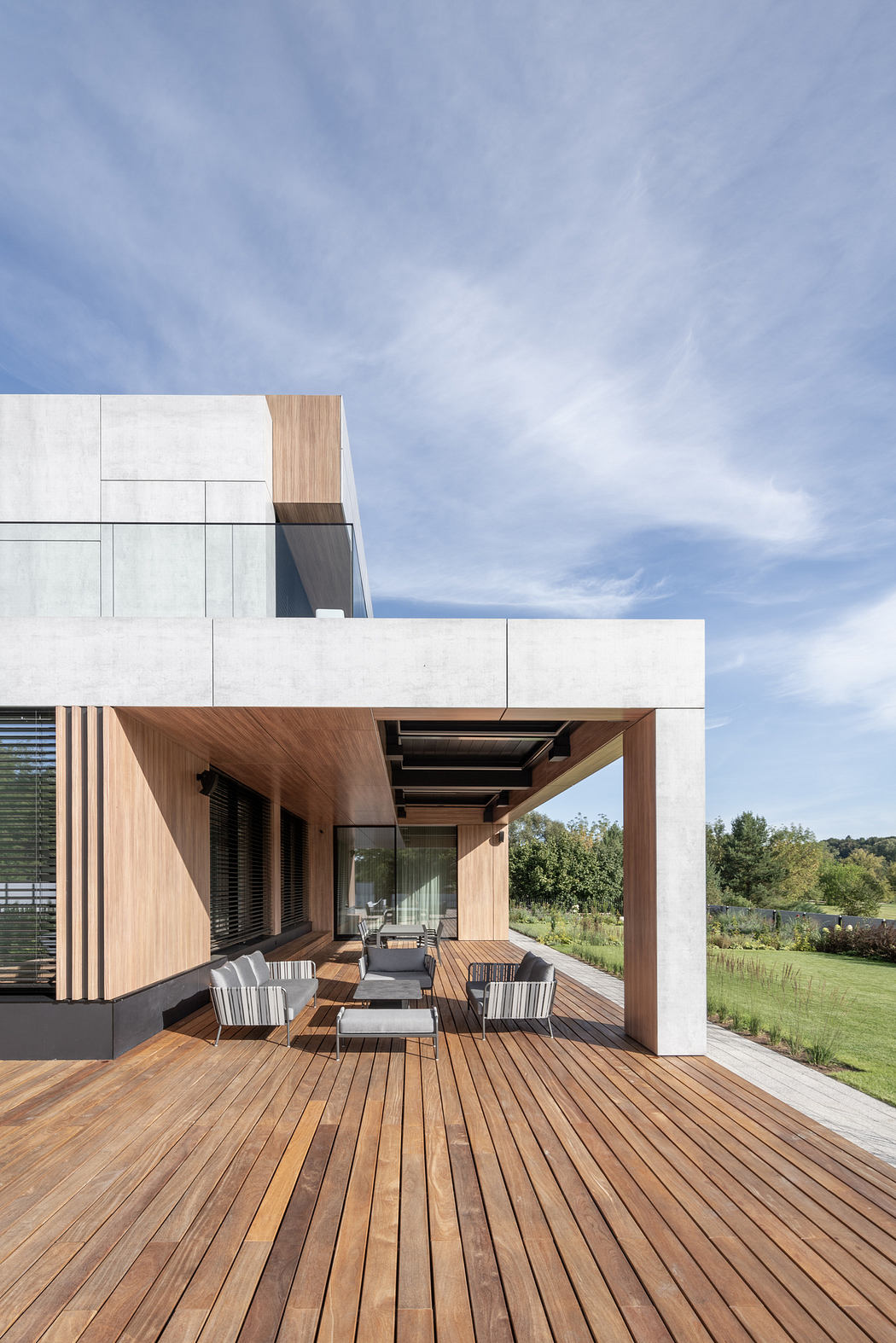 Modern terrace with wooden decking and outdoor furniture, overlooking greenery.