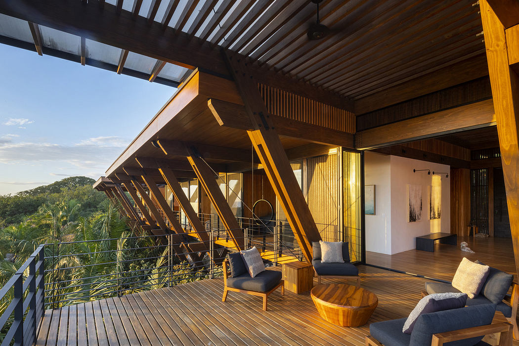 Wooden terrace with chairs overlooking a forest from a modern house.